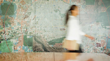 Mixed race businesswoman walking in conference table with map in background